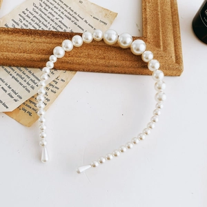 Close-up of elegant gradient white faux pearls on a headband with vintage book background