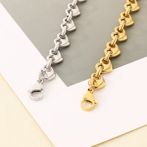 Detailed view of interconnected heart chain bracelets in polished gold and silver finishes