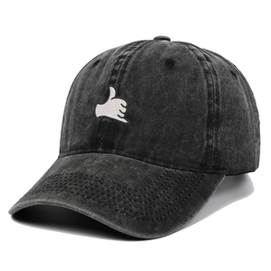 Detail of dark gray washed denim baseball cap with white hand gesture embroidery