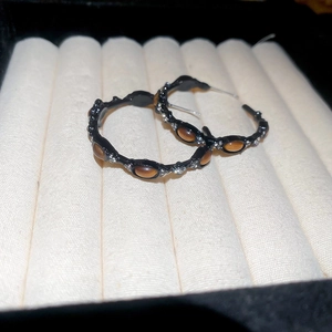 Close-up of vintage hoop earrings with brown tiger eye stones and sparkling diamonds