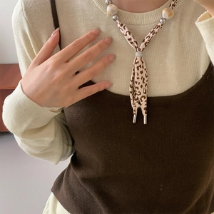 Close-up of leopard print fabric necklace with large resin beads on knit sweater
