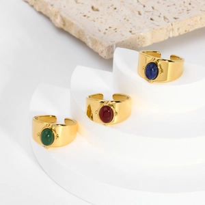 Detailed macro view of three wide gold rings with oval green red and blue gemstones
