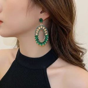 Vintage emerald crystal oval earrings with gold plating and rhinestones on model