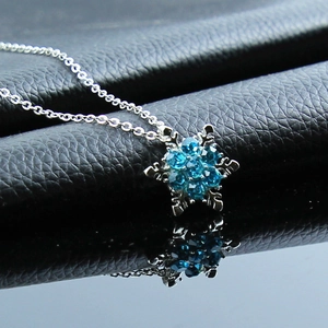 Detailed view of Frozen snowflake necklace with blue crystals on dark leather background