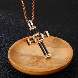 Detail of a punk style black and gold hollow cross pendant on a gold twisted chain