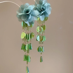 Detail of green chiffon flower earrings with shimmering sequins and gold chain tassels