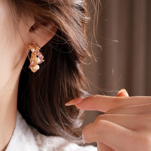 Close-up of gold plated flower earrings with strawberry crystal and pearls on model