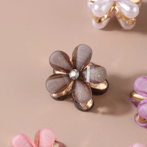 Macro detail of cat-eye resin flower hair claw with rhinestone and glitter finish