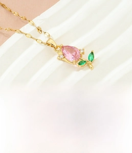 Close-up of tulip flower pendant with pink crystal and green leaves on gold chain