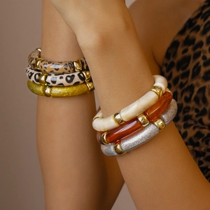 Close-up of stacked acrylic bangles featuring leopard print and gold glitter rings