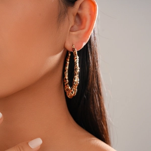Gros plan de boucles d'oreilles créoles dorées à motif léopard portées par un mannequin
