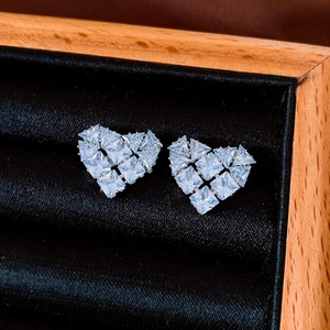 Macro shot of heart-shaped earrings with geometric cubic zirconia in silver prongs