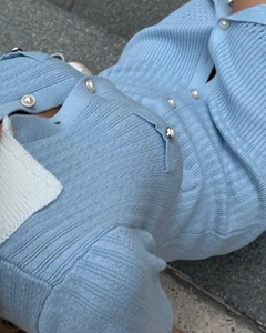 Macro shot of light blue knit fabric with white polo collar and pearl button details