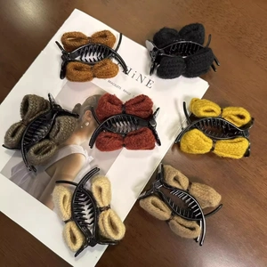 Detailed view of various knitted bow hair claws in brown, black, red, and beige colors