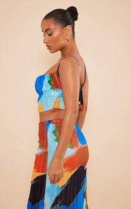 Detailed side view of pleated two-piece set with abstract print and spaghetti strap top
