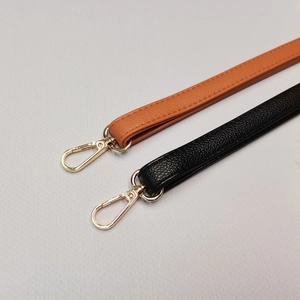 Détails des bandoulières en cuir grainé noir et marron avec fermoirs dorés