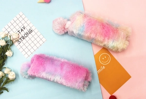 Close-up of soft plush pencil cases with colorful rainbow tie-dye fur and fluffy pom-pom