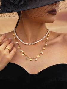 Detail of layered baroque pearl necklace with golden charm and teardrop pendant