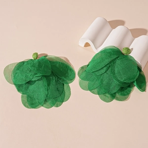 Macro shot of layered green organza petals and woven beads on artistic summer earrings