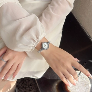 Detail of elegant silver bracelet watch with white dial and matching diamond ring on wrist