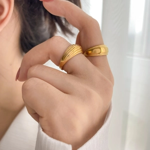 Detail of gold seashell texture ring and croissant style beaded edge ring on finger