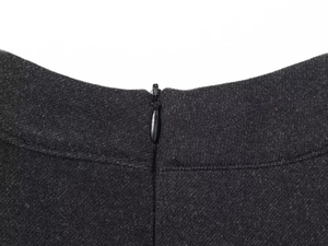 Detail of hidden zipper and black wool fabric texture on a stylish belted dress