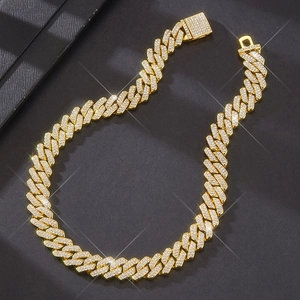 Macro shot of 14mm gold-plated Cuban link necklace with sparkling crystals on dark background