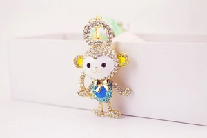 Detailed macro view of a golden crystal-studded monkey keychain with colorful enamel details