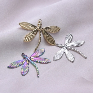 Macro shot of three dragonfly pendants in gold, silver, and iridescent finishes on silk