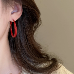 Model wearing a large cherry red glossy C-shaped hoop earring for a retro commute style