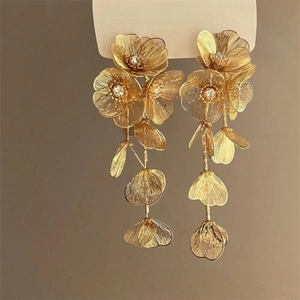 Detailed macro view of golden rose petal tassel earrings with brushed metal texture