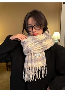 Detail of beige and grey check scarf with colorful dots and fringe on black coat