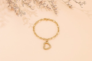 Macro view of a gold hollow heart pendant on a stylish chunky link chain bracelet