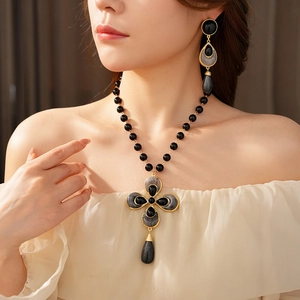 Detail of vintage flower clover jewelry set with black stones and golden metal finish