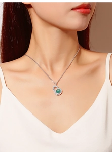 Macro detail of S925 sterling silver gourd pendant with green stone on model's neck