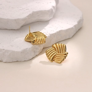Detailed view of irregular 18K gold plated stainless steel stud earrings on white stone
