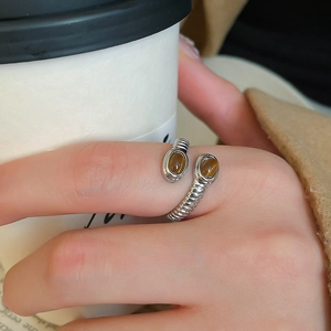 Detail of cross spiral silver ring with oval tiger eye stones worn by a model