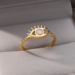 Macro detail of gold evil eye ring with moonstone and twisted rope band in jewelry box