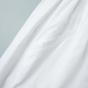 Détail de la poche latérale et des coutures fines sur une robe blanche en coton