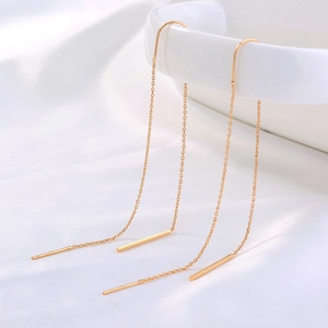 Detail view of gold S925 sterling silver drop earrings on a white silk background