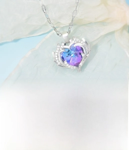 Macro shot of colorful heart crystal pendant with silver winged rhinestone frame and chain