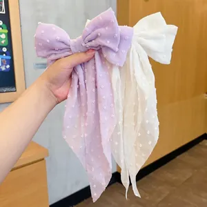 Detail of oversized purple and white chiffon bow clips with dotted texture and long ribbons