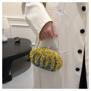 Detail of beaded evening bag featuring yellow and green feather patterns and gold ring handle