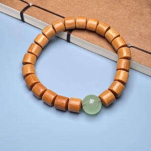 Detailed shot of sandalwood cylinder beads with a translucent green gemstone bead