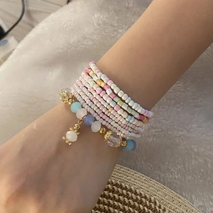 Detail of bohemian multilayer beaded bracelet with colorful seeds and gold charms