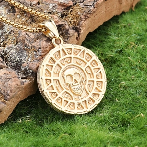 Detail of vintage gold skull coin pendant with Nordic motifs on natural mossy background