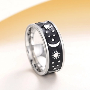 Macro shot of silver ring with celestial sun, moon and star patterns on black band