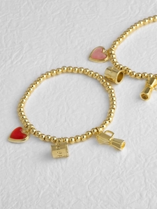 Detalle de la pulsera de cuentas bañada en oro de 18k con dijes de corazón y cafetera