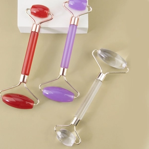 Dual-head natural stone facial massagers in red, purple, and clear quartz with gold metal