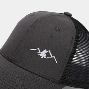 Macro detail of mountain embroidery and breathable mesh on a gray trucker hat
